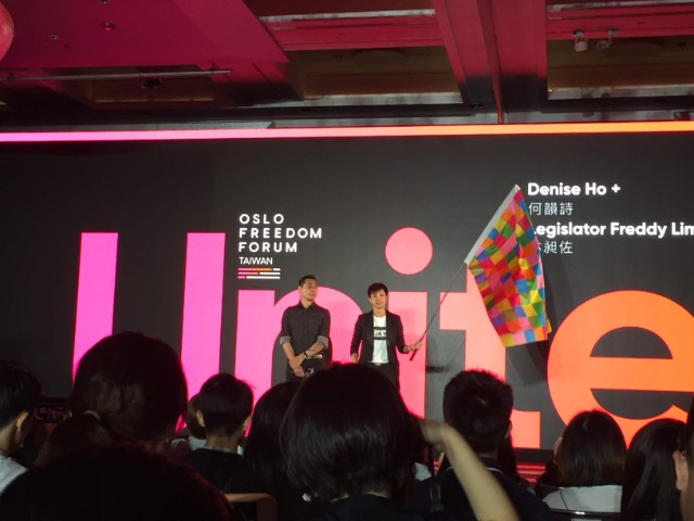 何韻詩帶著藝術家巴丟草做的「連儂牆旗幟」上台。