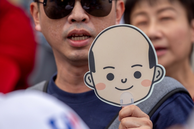 高雄市長韓國瑜參選總統失利，現在又面臨高雄人的罷免行動。圖為支持者舉著韓國瑜卡通頭像。