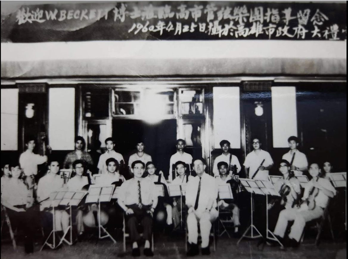 1960年4月25日，美國音樂家 W. Beckett 博士（前右）在高雄市政府大禮堂與呂炳川指揮（前左）和「高雄市立管絃樂團」指導留念。